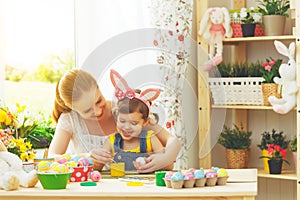 Happy family mother and child girl paints eggs for Easter