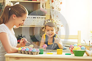 Happy family mother and child girl paints eggs for Easter