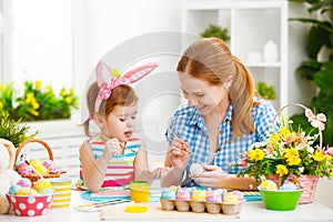 Happy family mother and child girl paints eggs for Easter