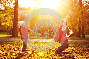 Happy family mother and child girl playing and throw leaves in a