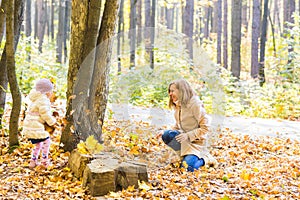 Happy family mother and child girl playing throw leaves in autumn park outdoors