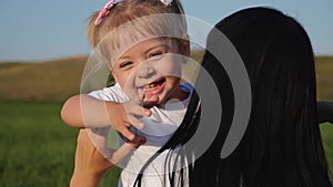 Happy family, mother and child have fun outdoors in the Park. The little lovely blonde girl is having fun and hugs and