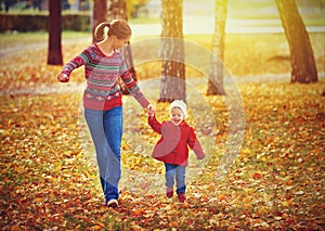 Famiglia felice madre un poco sul autunno a piedi 