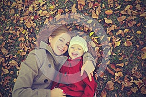 Happy family: mother and child little daughter play cuddling on autumn