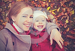 Happy family: mother and child little daughter play cuddling on autumn