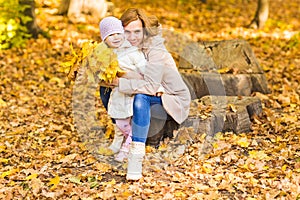 Happy family: mother and child little daughter play, laughing cuddling on autumn walk in nature outdoors