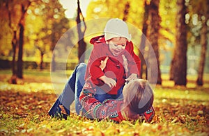 Happy family: mother and child little daughter playing and laughing in autumn