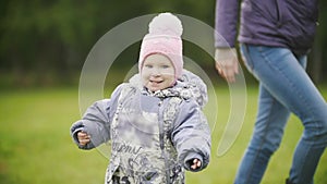 Happy family: Mother and child - little girl walking in autumn park: baby close up, slow motion