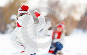 Happy family mother and child playing snowballs on winter walk