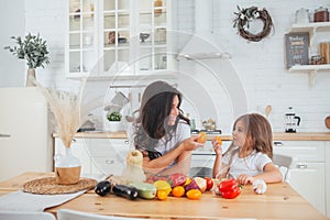 Happy family mother and child posing at home. Beautiful young mom and little daughter having fun and preparing