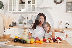 Happy family mother and child posing at home. Beautiful young mom and little daughter having fun and preparing vegetables for