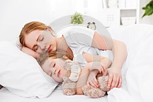 Happy family mother and child sleeping in bed