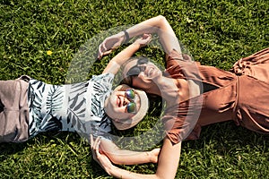 Happy family: mother and child son laughing, lying on the green grass in nature.
