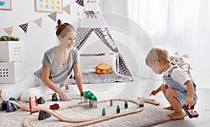 Happy family mother and child son playing in toy railway in pl