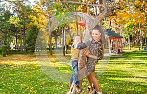 Happy family: mother and child sonr have fun in autumn on autumn park. Young Mother and kid girl hugging in leaves at fall.