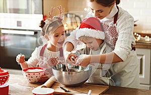 Happy family mother and children bake christmas cookies