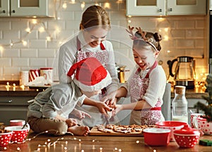 Happy family mother and children bake christmas cookies