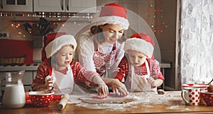 Happy family mother and children bake cookies for Christmas