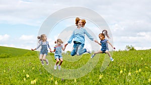 Happy family mother and children daughter girls laughing and jump on meadow in summer photo