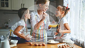 Happy family mother and children twins bake kneading dough in