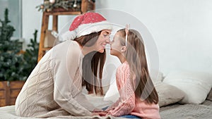 Happy family mother and cute daughter smiling playing touching nose celebrating Christmas holiday