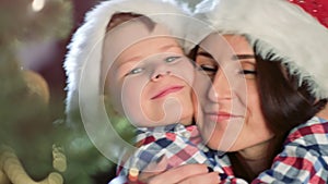 Happy family mother and cute little son hugging and smiling together near Christmas tree close-up