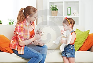 Happy family mother and daughter child girl playing with toy ted