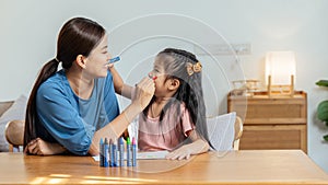 Happy family. Mother and daughter drawing together. Adult woman helping to child girl