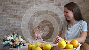 Happy family mother and daughter little girl, eat healthy vegetarian food, lots of fruit