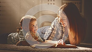 Happy family mother and daughter read a book in evening