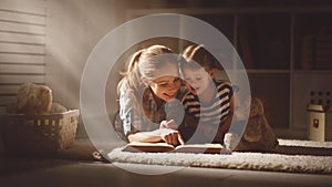 Happy family mother and daughter read a book in evening