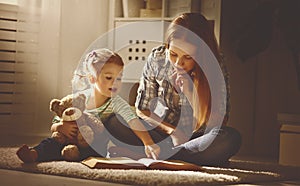 Happy family mother and daughter read a book in evening