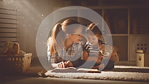 Happy family mother and daughter read a book in evening