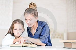 Happy family mother and daughter read a book in the evening at home. the concept of family comfort and family relations