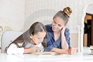 Happy family mother and daughter read a book in the evening at home. the concept of family comfort and family relations
