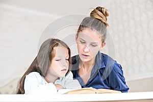 Happy family mother and daughter read a book in the evening at home. the concept of family comfort and family relations