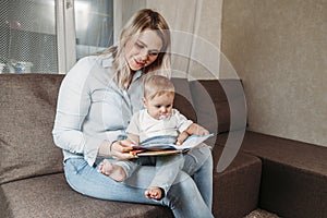 Happy family mother and daughter read a book in the evening at home sitting on the couch