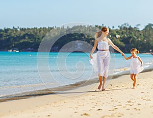 Happy family mother and daughter run, laugh and play at beach