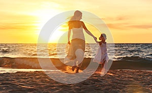 Happy family mother and daughter run, laugh and play at beach