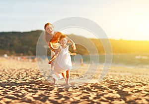 Happy family mother and daughter run, laugh and play at beach