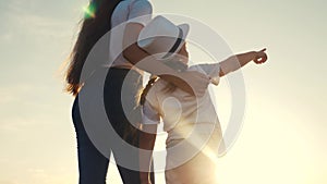 Happy family mother and daughter by the sea at sunset silhouette. mother and child kid reach out to sun. kid dream