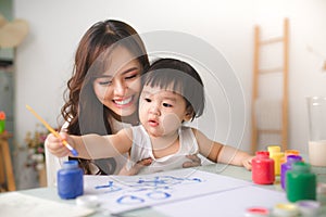 Happy family mother and daughter together paint. Asian woman helps her child girl. photo