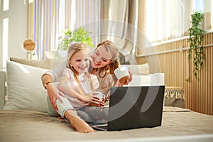 Happy family mother with daughter using computer laptop at home, modern lifestyle