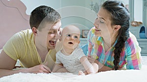 Happy family - mother, father and baby on the bed