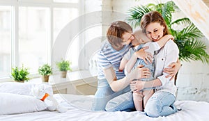 Happy family mother father and baby in bed