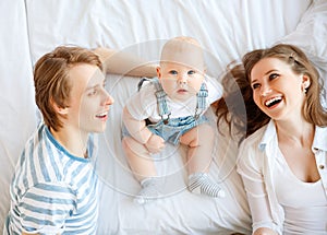 Happy family mother father and baby in bed