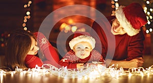 Happy family mother father and baby at christmas tree at home