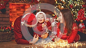 Happy family mother father and baby at christmas tree at home
