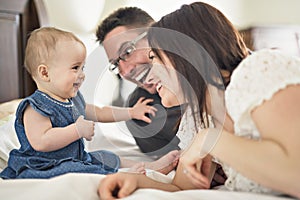 Happy family mother, father and baby at home in bed