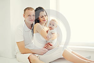 Happy family, mother and father with baby home in white room